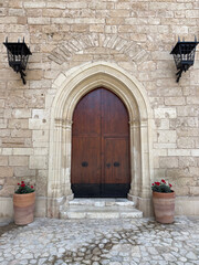 Fototapeta na wymiar Solid Wood Doors with Medieval Stone Gothic Arch and Black Iron Lamps in Spanish Castle, Portrait