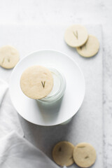Top view of cut out rosemary sugar cookies on a milk bottle, rosemary cookie  on milk on a white background, flatlay of herb sugar cookies