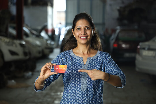 Indian happy customer showing the credit or a debit card for digital payment. Portraying customer trust towards online payment to the service station