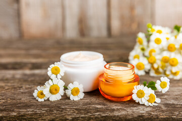 Obraz na płótnie Canvas Open jar of cream for face, body and hands with chamomile flower on a wooden background. Herbal dermatological cosmetic hygiene cream. Natural cosmetic product. Beauty concept. Cosmetic tube.MOCKUP.