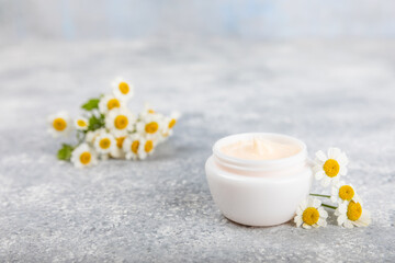 Obraz na płótnie Canvas Open jar of cream for face, body and hands with chamomile flower on a blue background. Herbal dermatological cosmetic hygiene cream. Natural cosmetic product. Beauty concept. Cosmetic tube.MOCKUP