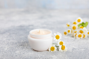 Fototapeta na wymiar Open jar of cream for face, body and hands with chamomile flower on a blue background. Herbal dermatological cosmetic hygiene cream. Natural cosmetic product. Beauty concept. Cosmetic tube.MOCKUP