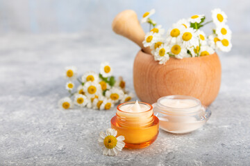 Fototapeta na wymiar Open jar of cream for face, body and hands with chamomile flower on a blue background. Herbal dermatological cosmetic hygiene cream. Natural cosmetic product. Beauty concept. Cosmetic tube.MOCKUP
