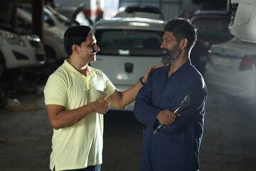 car mechanic standing with the happy customer shaking hands together. Portraying customer satisfaction to the whole scene the customer