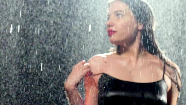 Woman with long brunette hair standing under hard downpour. Strapless female shoulder with birthmark washed by heavy rain
