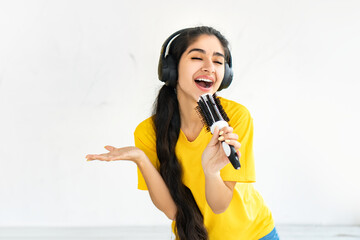 Carefree woman in headphones sing song in hairbrush like in microphone