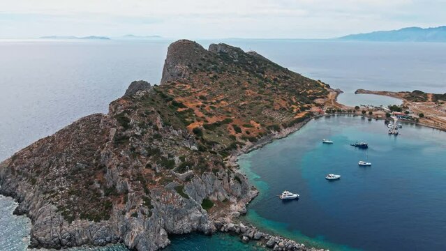 filming from above, aerial view of beautiful, colorful and turquoise sea bay with boats and yachts surrounded cliffs. Mediterranean sea coast, Knidos Ancient city, Datca, Turkey.