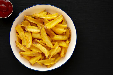 Homemade French Fries on a Plate on a black background, top view. Flat lay, overhead, from above. Copy space.