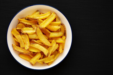 Homemade French Fries on a Plate on a black background, top view.