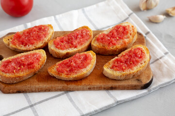 Homemade Pan Con Tomate (Tomato Toast) on a Rustic Wooden Board, side view.