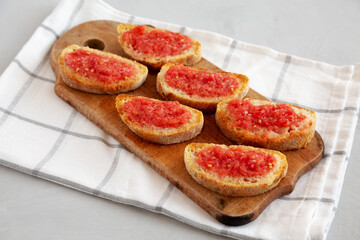 Homemade Pan Con Tomate (Tomato Toast) on a Rustic Wooden Board, side view.