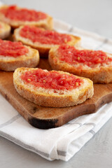 Fototapeta na wymiar Homemade Pan Con Tomate (Tomato Toast) on a Rustic Wooden Board, side view. Close-up.