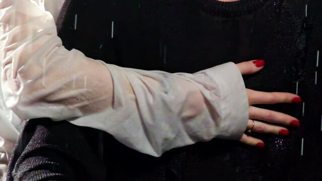 Sparkle drops of water fall on people in room. Woman hand in wet blouse with bright manicure and ring with stone hugs man