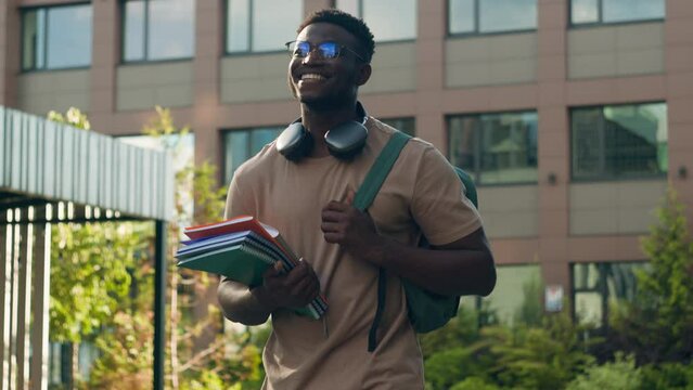 African American happy smiling student guy ethnic university man male with backpack school bag and books smile walking in city outdoors in academy college university campus on education class lesson