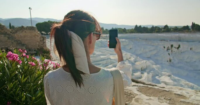 Woman take photo for social media with travertine pools limestone terraces in Pamukkale, Turkey travel 