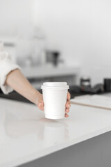Closeup of hand serving white coffee cup with beautiful Asian woman barista