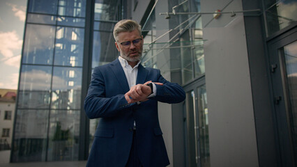 Relaxed middle-aged man senior mature business employer businessman walking in city outdoors near...