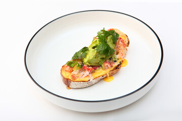 Crab meat bruschetta. Served on white plate with mashed avocado, tomatoes and herbs. Delicious crab dish.Copy space. Isolated object.