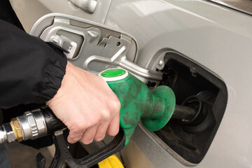 A man hand holding pump filling gasoline. Pumping petrol into the tank. A car refuel on gas station