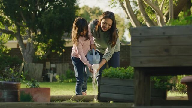 Mom and daughter watering their veggie patch together