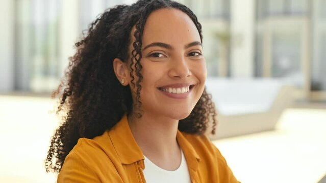 Close-up video portrait of gorgeous young hispanic or brazilian curly woman, looking at camera with charming cute toothy smile, posing in casual stylish wear outdoors. Female student or freelancer
