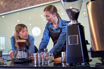Two barista girl talking in cafe and coffee machine time to waiting customer
