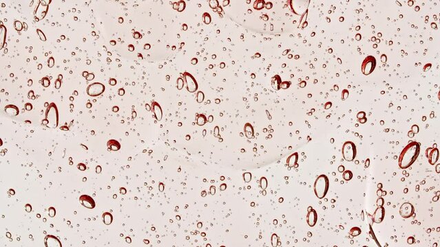 Pink Transparent Cosmetic Gel Fluid With Molecule Bubbles Flowing On The Plain White Surface. Macro Shot. High quality 4k footage