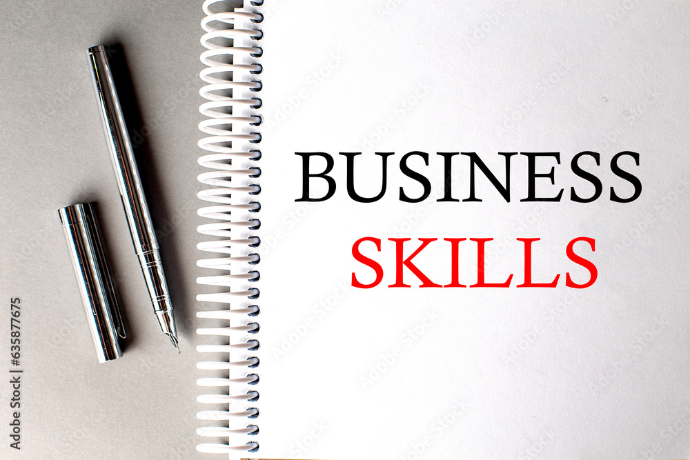Poster business skills text on a notebook with pen on grey background