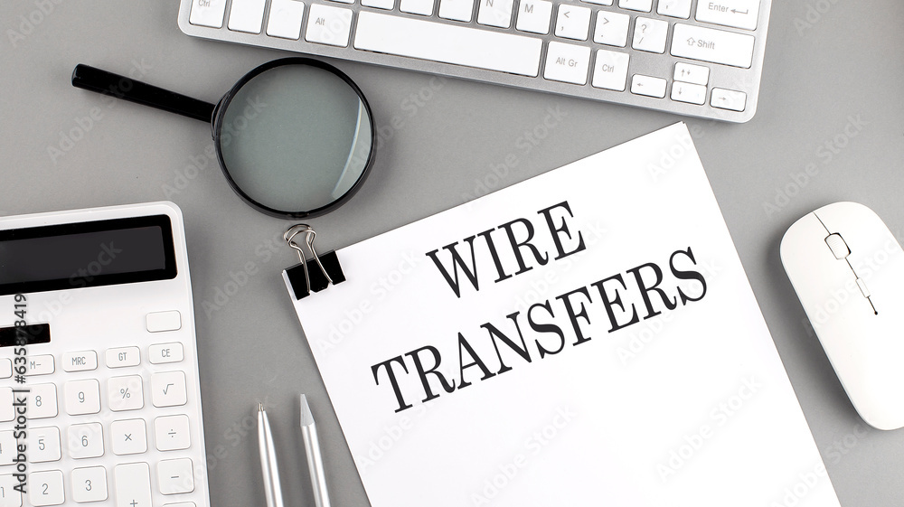 Poster wire transfers written on paper with office tools and keyboard on the grey background