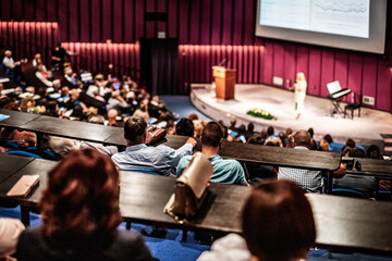 Business and entrepreneurship symposium. Female speaker giving a talk at business meeting. Audience...