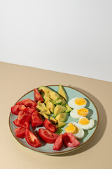 Healthy vegetarian salad breakfast. Tomato, avocado and boiled eggs on plate