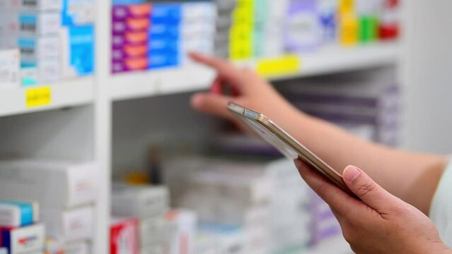 Pharmacist using computer tablet for check stock of medicine in pharmacy drugstore shelves .Online medical concept.
