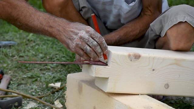 Carpenter measures angle and draw marks on wooden pole joint, use of steel square and pencil