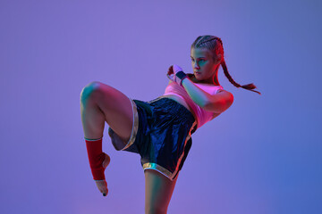Leg kick. Sportive teen girl, mma fighter athlete in motion, training, fighting against purple...