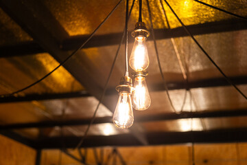 Classic style ceiling lighting bulbs during glowing in warm light shade, interior decoration object equipment. Selective focus, photo contain some noise due to low light environment.