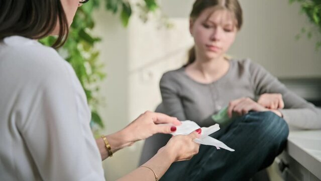 Mother showing telling preteen daughter sanitary pads