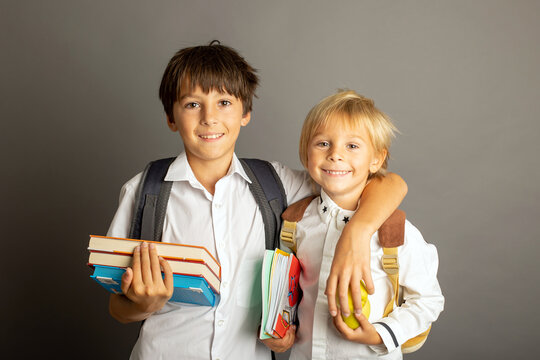 Cute preschool blond child, boy, holding books and notebook, apple, wearing glasses, ready for school