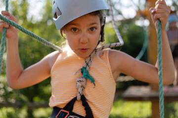 Little Girl Having Fun in a Rope Park Trail Facility. Happy little child enjoying climbing in an...