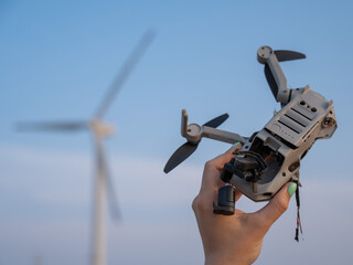 Woman holding a crashed drone against the backdrop of windmills. 