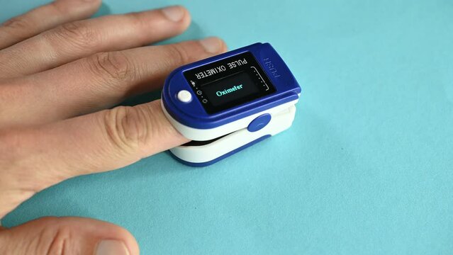 Pulse oximeter for measuring blood oxygenation pulse on a man's hand.