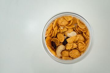 Top view of bake corn flakes, nut and raisin are mixed in the box, placed on white table with copy pace. Food object photo.