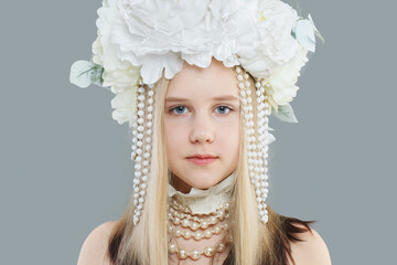 Vintage portrait of young perfect blonde girl in pearls and white flower hat on grey background