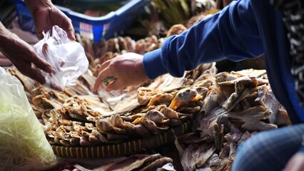 Female hand choosing the dried fish that is put on for food preservation at the traditional market, Indonesia.