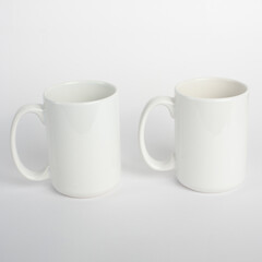 Two mugs mockup isolated on light gray background. White blank cups for your design. Empty mockup template on a white table