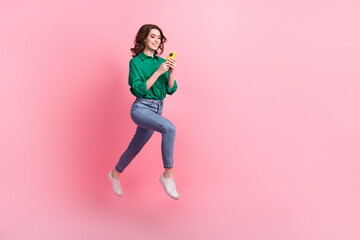 Full length portrait of active charming person jumping running empty space use smart phone isolated on pink color background