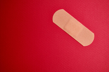 Medical plaster on a red background. Blood donation, space for text. Health and medicine concept
