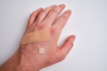 Male hand with a medical adhesive plaster close-up. Adhesive plaster on damaged skin. First aid for...