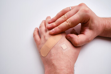 Male hand with a medical adhesive plaster close-up. Adhesive plaster on damaged skin. First aid for wounds and cuts