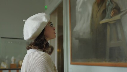 Young woman looking at a painting in a Parisian gallery, France