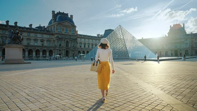 Beautiful girl walking in the square near the Louvre in the evening, Paris